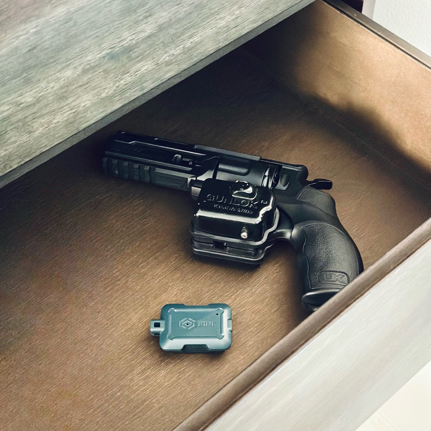 Gray Kini Motion Sensor in drawer next to Gun with Trigger Lock (Mobile)