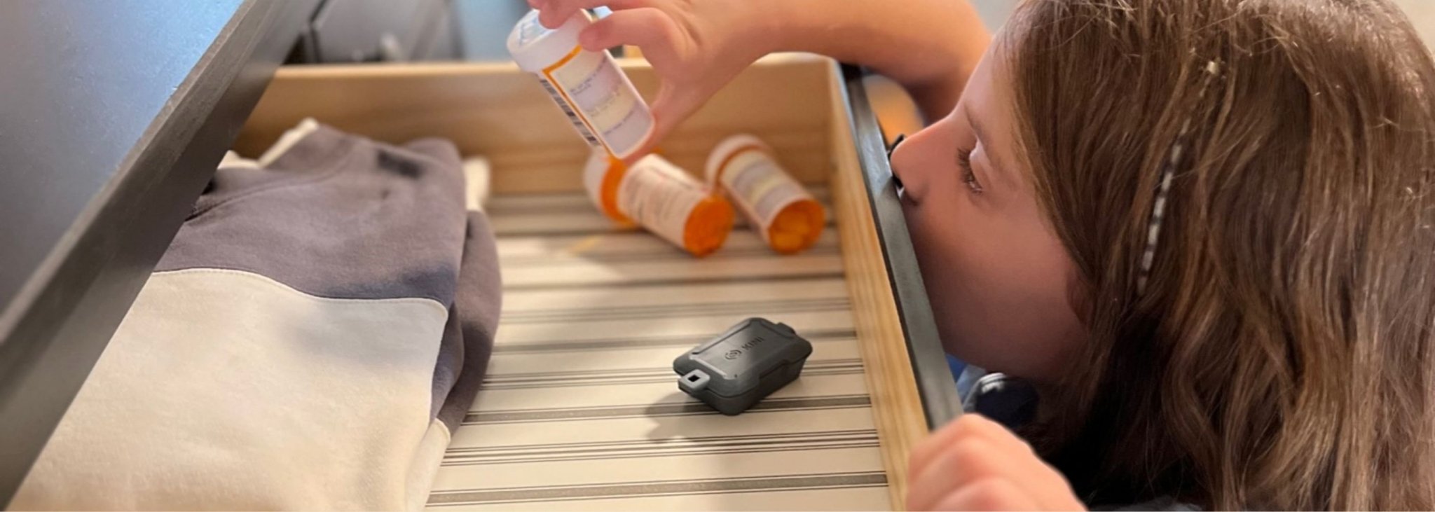 Gray Kini Wireless Motion Sensor in drawer with Girl Discovering Pill Bottle (desktop)