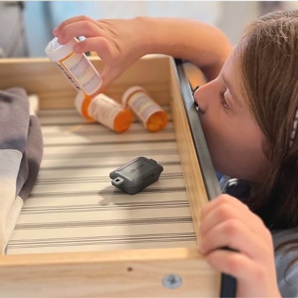 Gray Kini Wireless Motion Sensor in drawer with Girl Discovering Pill Bottle (mobile)